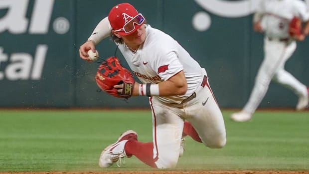 Arkansas second baseman Peyton Holt throws a runner out from his knees after a diving stop.